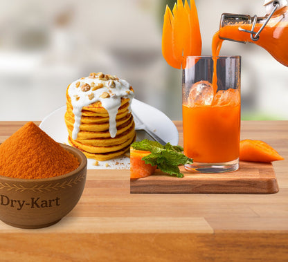 A bowl of carrot powder beside carrot pancakes and a glass of carrot juice.